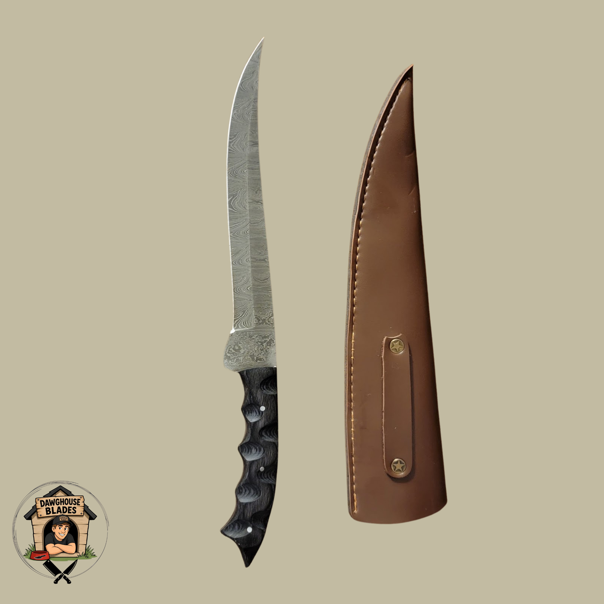 A fixed-blade knife with a patterned steel blade and black textured handle, shown next to its brown leather sheath on a solid beige background. A circular 'Kamikaze Village' logo is visible in the bottom-left corner.
